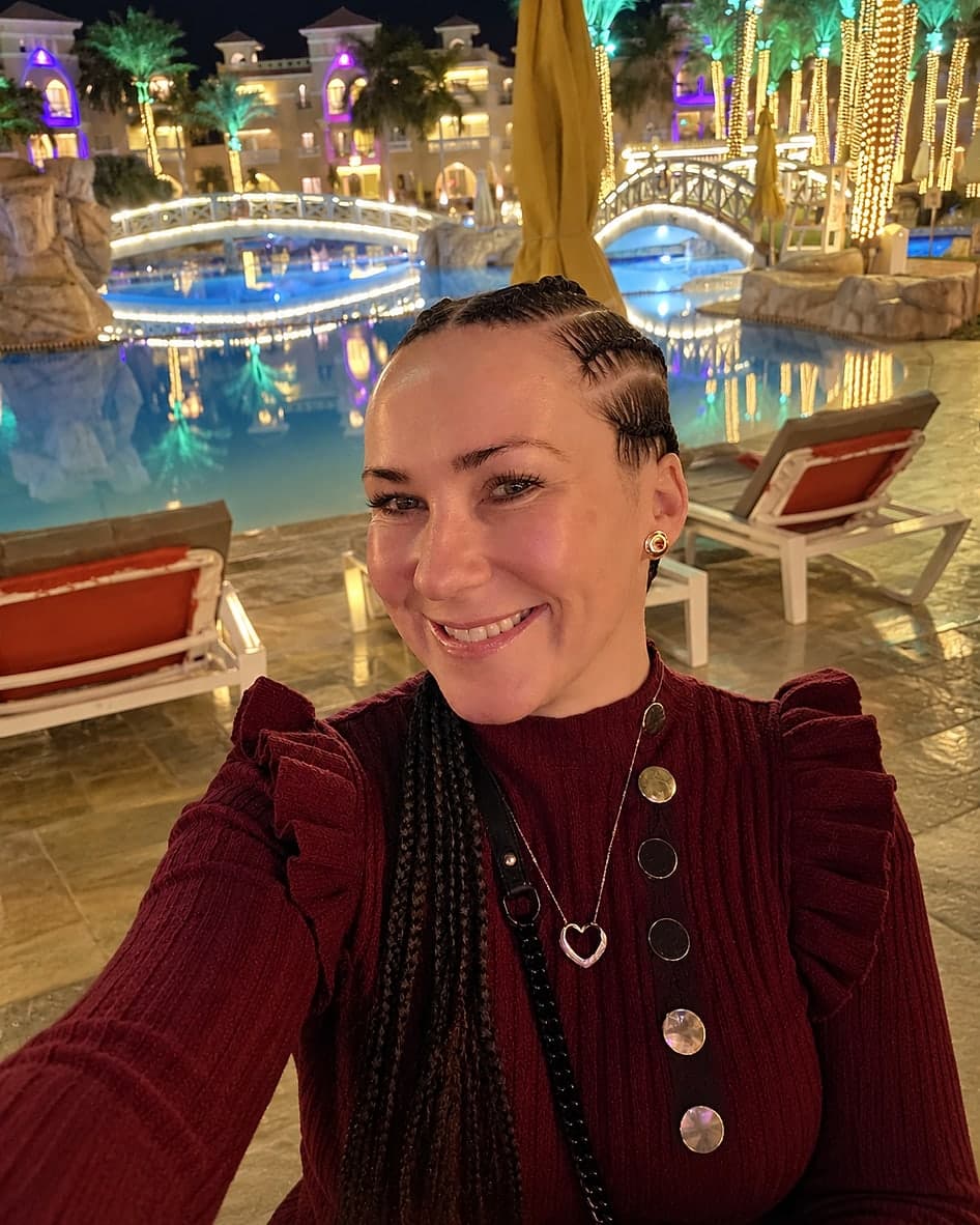 Victoria, founder of Victoria Travels and Events, smiling beside a lit resort pool at night